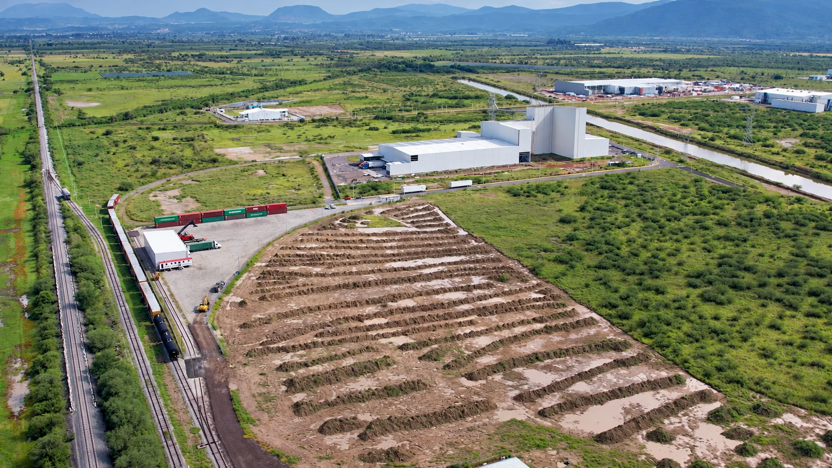 Vista aérea de la terminal PMO: vías férreas, patio de contenedores y naves del Centro Logístico Jalisco junto al canal